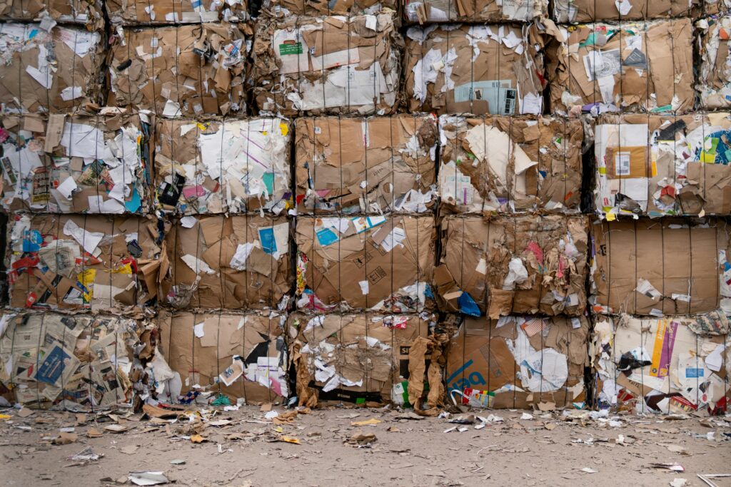 pexels-photo-2967770-2967770 Large bales of recycled cardboard stacked outdoors, ready for processing.